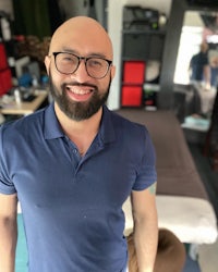 a bald man with glasses smiling in front of a room